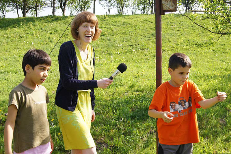 Mädchen mit einem Mikrofon in der Hand zwischen zwei Jungs
