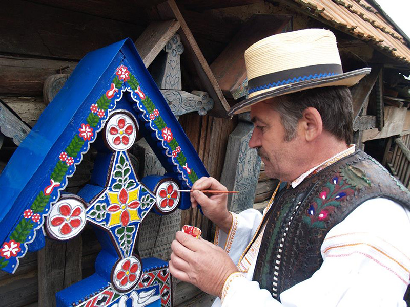 Maler bemalt ein Holzkreuze