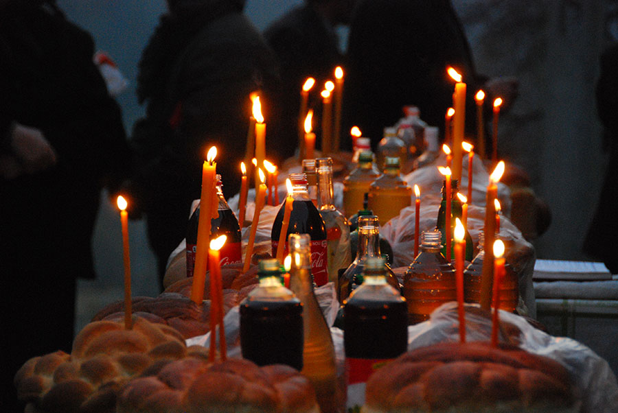 Kerzen zwischen Flaschen und Brot