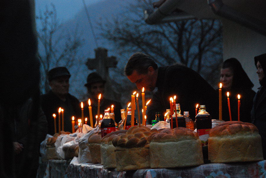Priester vor einem Tisch mit Kerzen, Brot und Flaschen