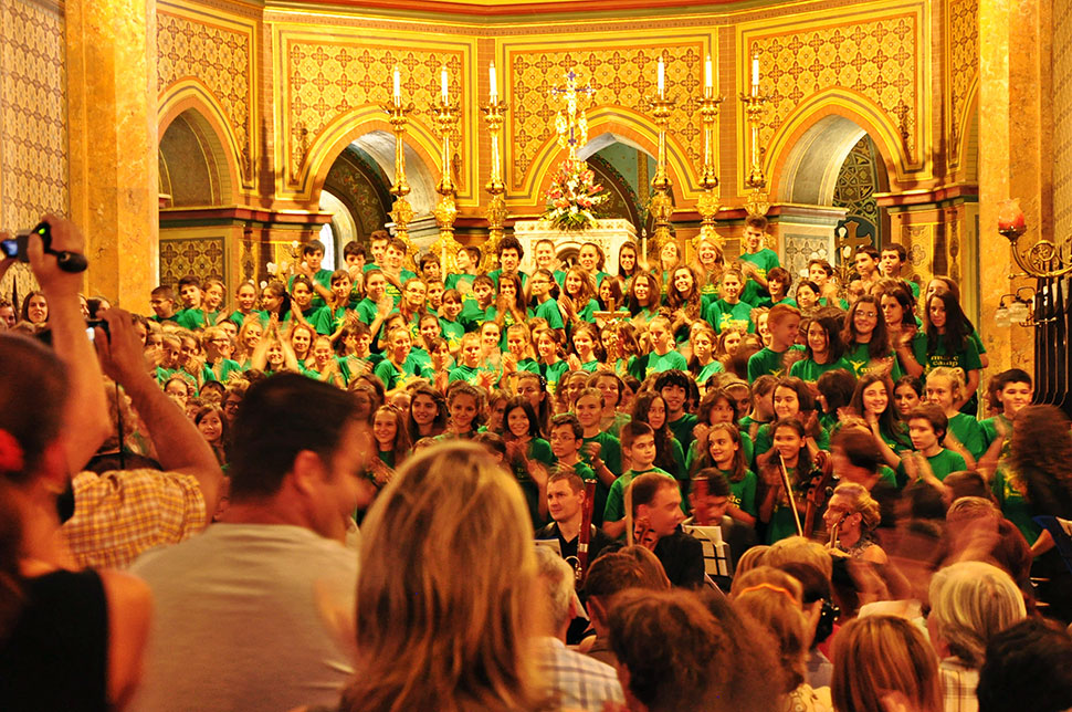 Kinder stehen mit fröhlichen Gesichtern und grünen T-Shirts vor dem Altar
