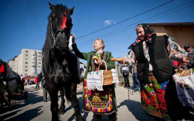 schwarzes Pferd neben zwei Frauenin Trachten