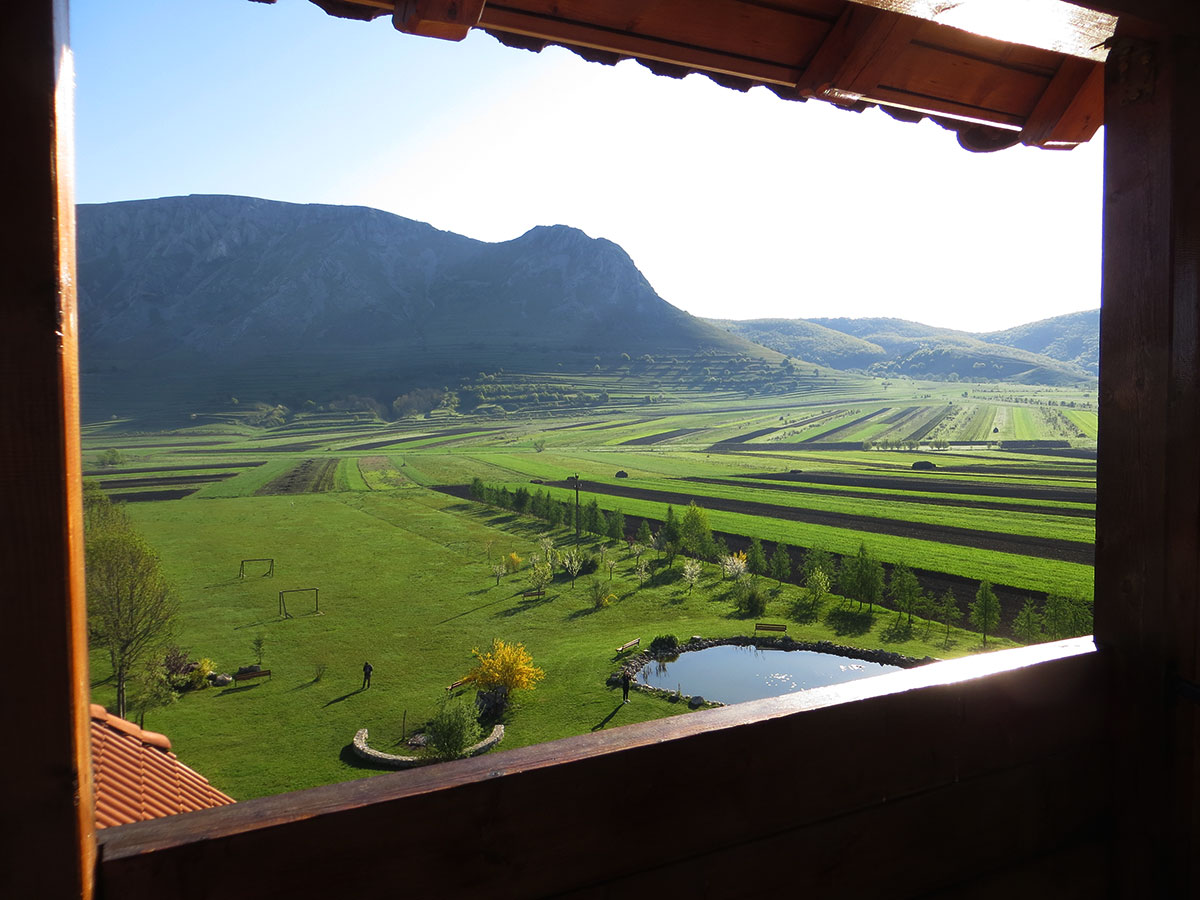Blick aus dem Fenster mit Feldern und Bergen im Hintergrund