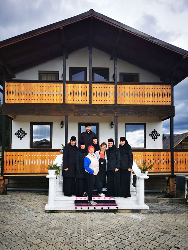 Nonnen und Mönch vor neuer Notunterkunft