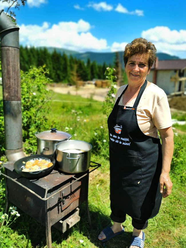 Frau kocht auf Holzherd im Freien