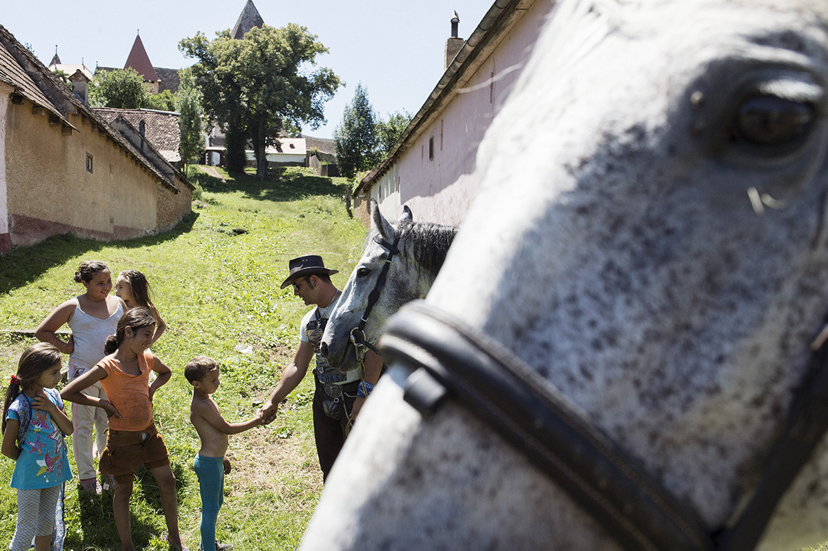 Mann begrüßt Kinde neben einem Pferd