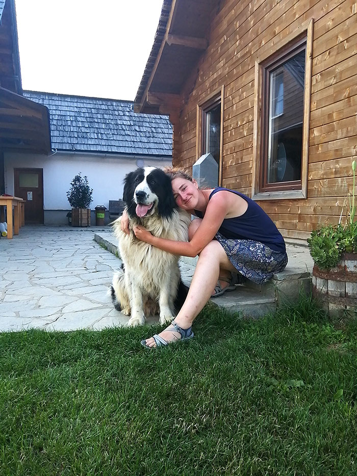 Anca sitzt auf einer Stufe vor einem Haus und hält einen Hund im Arm