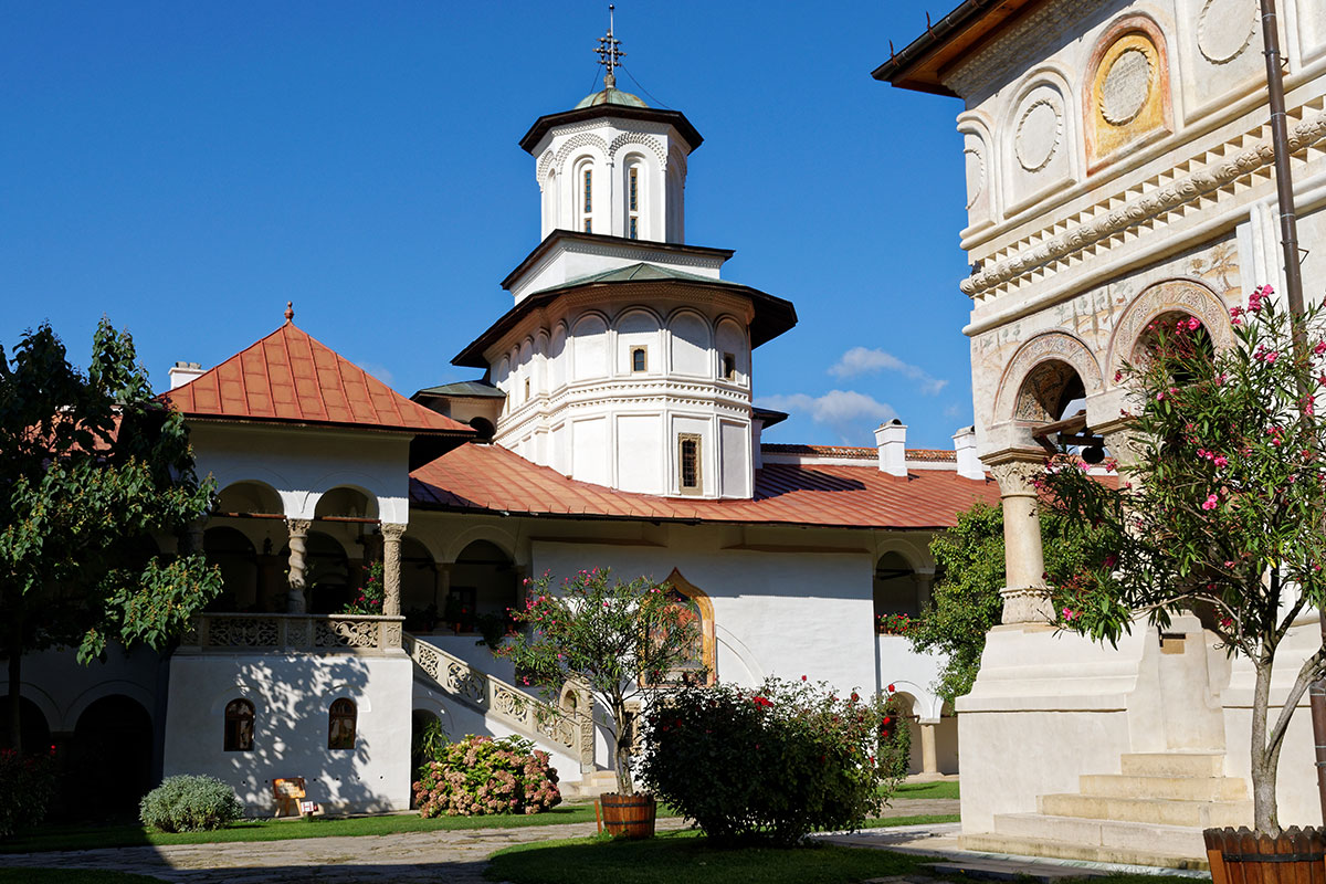 Nebengebäude eines Klosters mit Kirchentürmchen und Blumenpflanzen davor