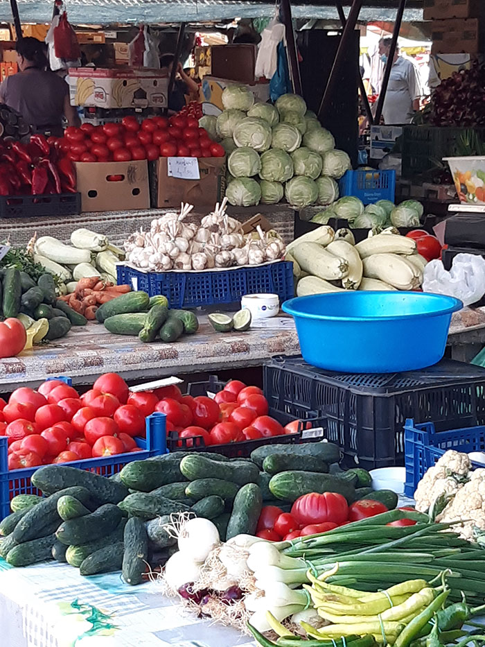 Marktstand mit buntem Gemüsesorten wie Gurken, Paprika, Tomaten, Kohlköpfen, Lauch und vielem mehr