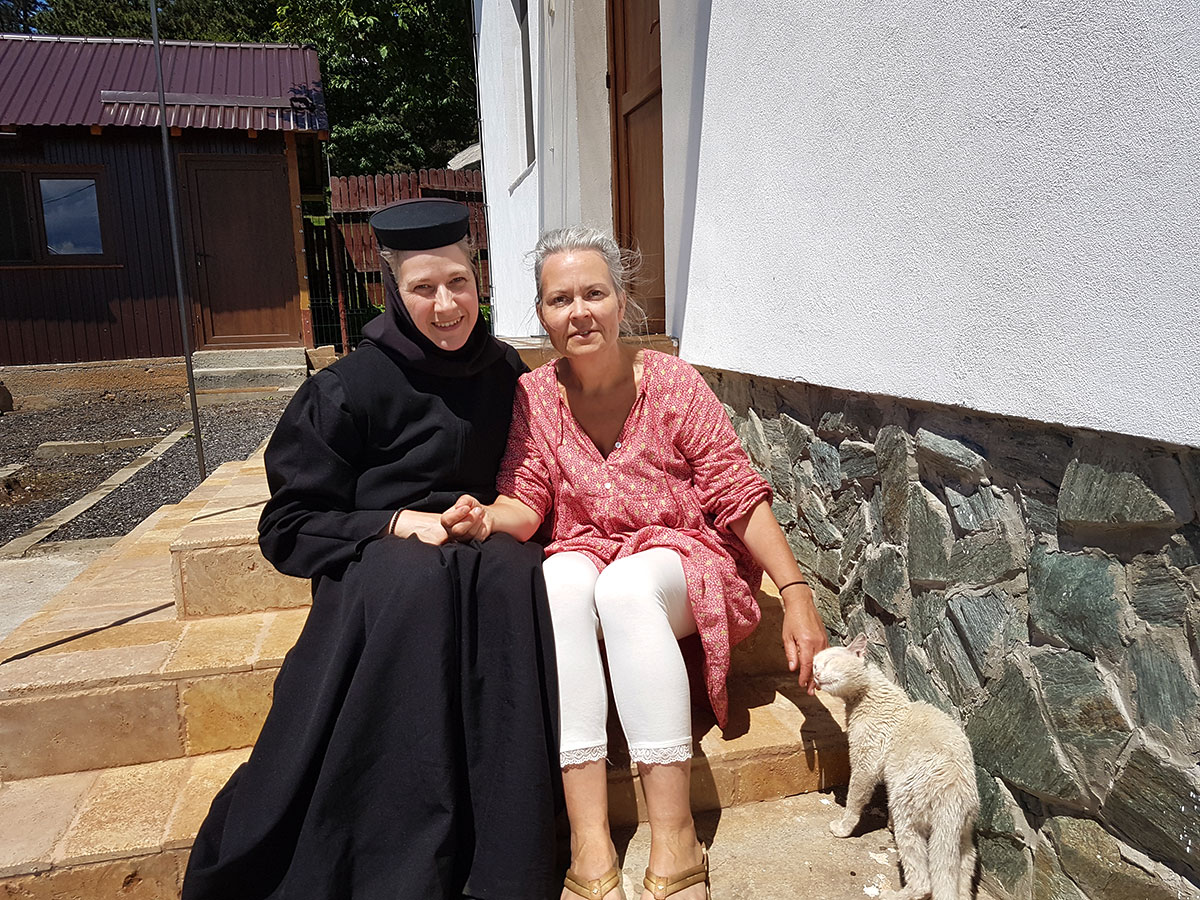 Nonne sitzt mit einer Frau auf einer Treppe