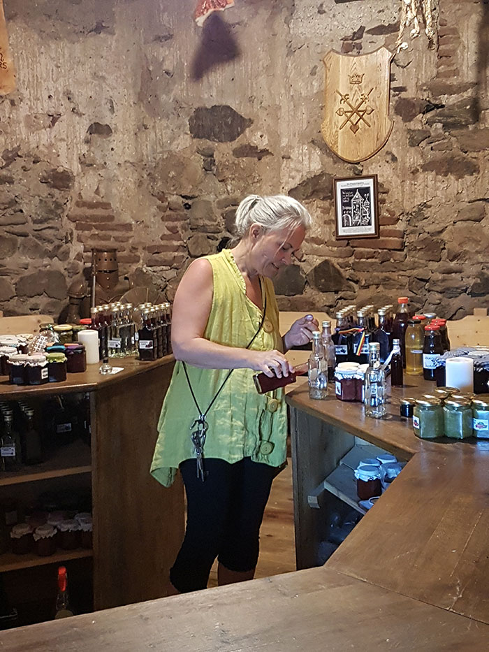 Frau steht an einer Bar und gießt Alkohol aus einer Flasche in ein Glas