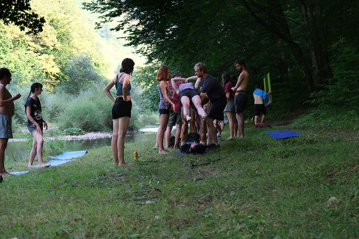 junge Menschen machen Yogaübungen neben einem Fluss