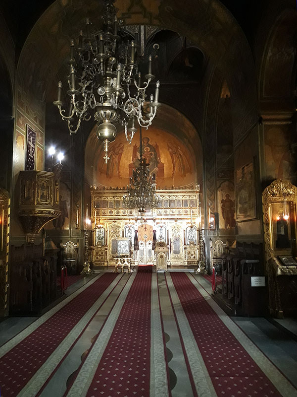 Innenraum der orthodoxen Kirche mit drei langen roten Teppichen und goldenem Altar im Hintergrund