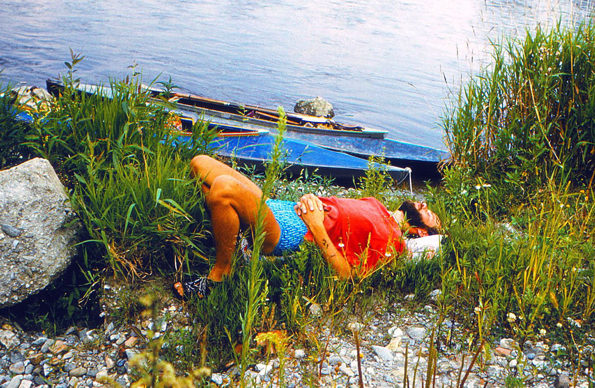 Paddler leigt neben einem Boot am Ufer
