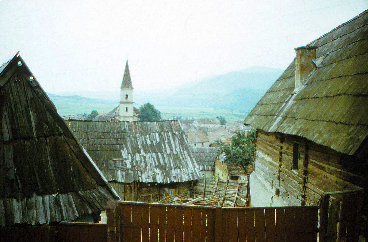 Holzhäuser vor einer Dorfkirche