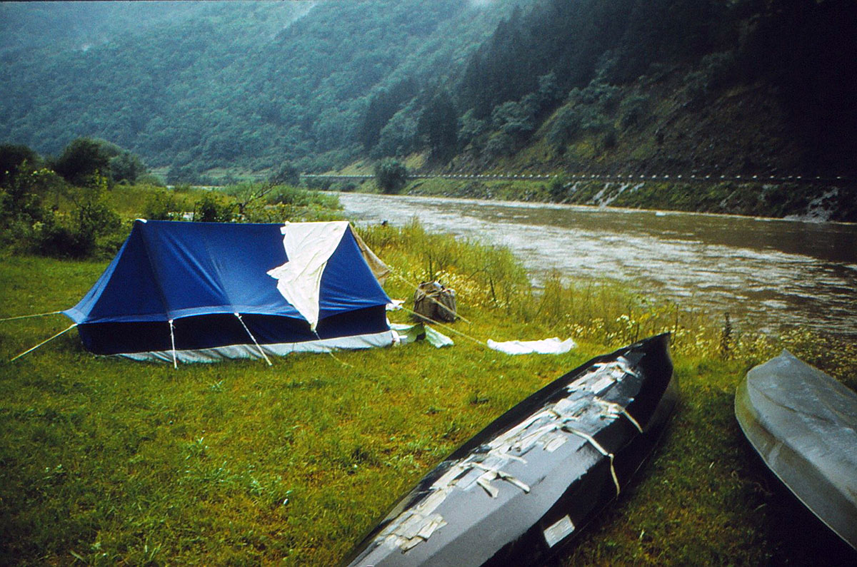 Paddelboot mit unzähligen Klebern auf der Bootshaut nebem einem Zelt auf der Wiese liegend