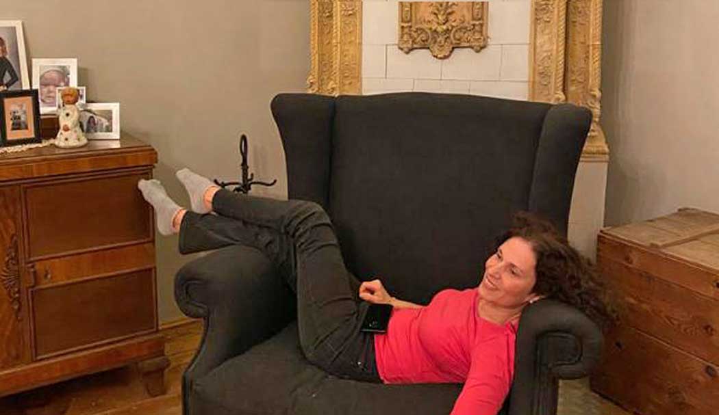 Frau liegt auf einem Sessel vor einem Ofen