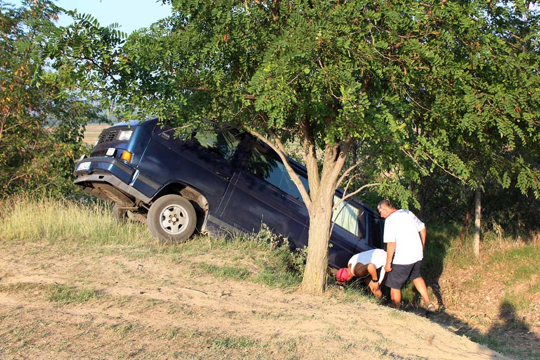 Menschen betrachten das Auto im Graben