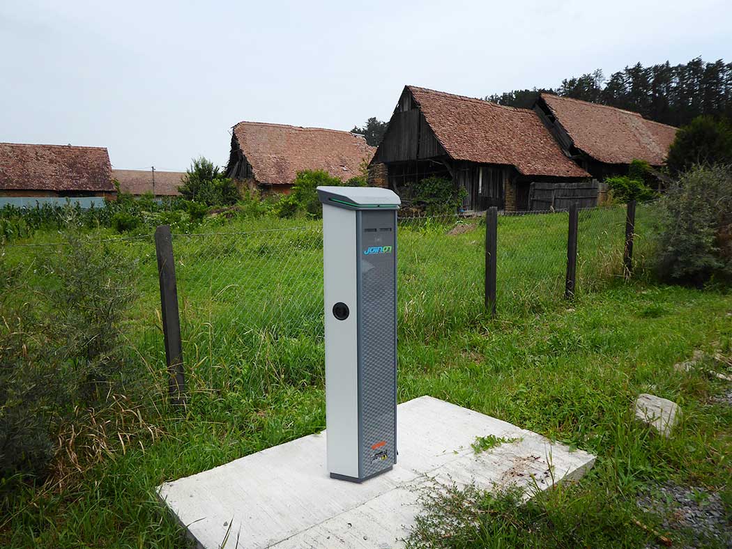 Ladesäule hinter einem Bauerngehöft