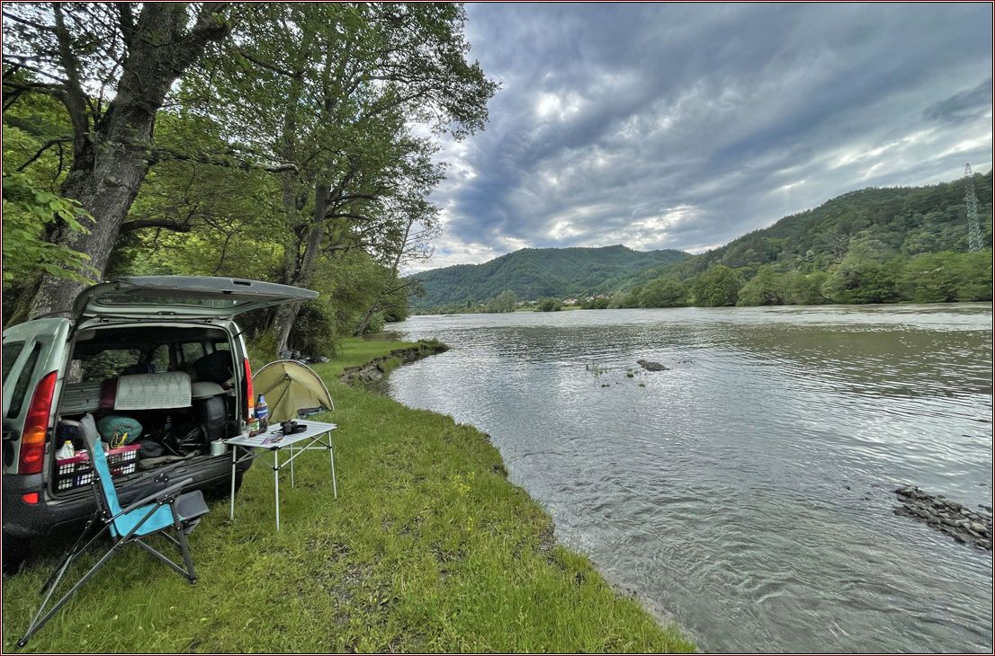 Auto und Zelt neben einem Fluss