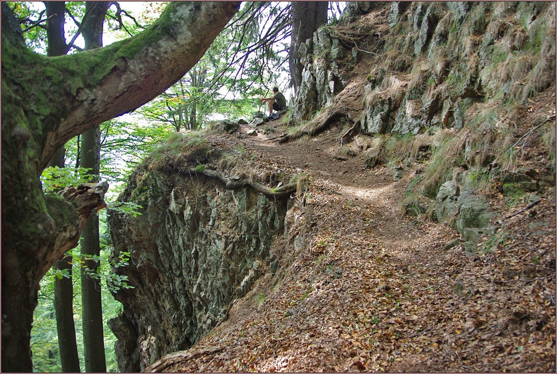 BWanderer sitzt auf einem Stein an einem Wanderweg