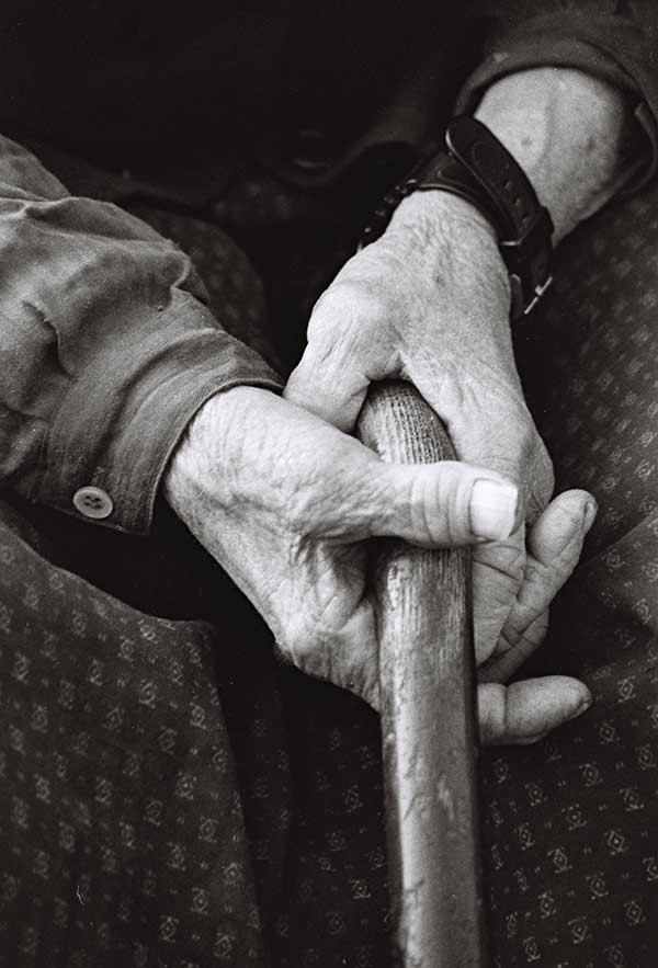 Hände eines alten Menschen mit einem Stock