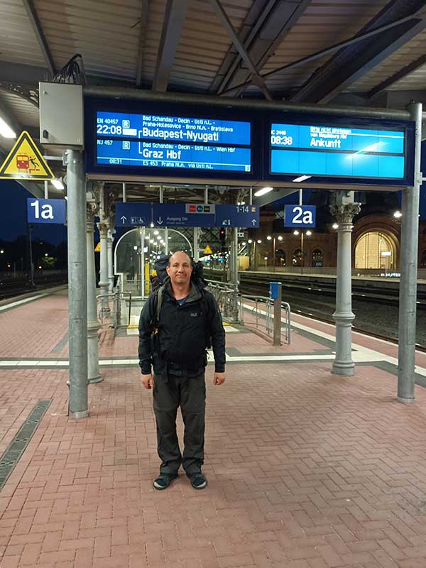 Stefan auf dem Bahnsteig unter einer Anzeigetafel